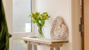 A wooden table with a vase of yellow flowers and a woven wall art piece. - 3 Bed in Cowes (oc-s32705) (Cowes)