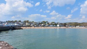A coastal town with a sandy beach, a rocky breakwater, and buildings along the shore. - 1 Bed in Saundersfoot (oc-pw282b) (Saundersfoot)