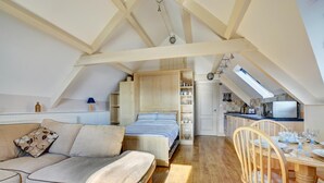 A loft-style bedroom with a bed, a sofa, and a dining area with a table and chairs. - 1 Bed in Saundersfoot (oc-pw282b) (Saundersfoot)