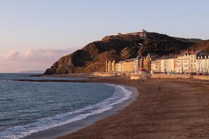 A coastal town with a prominent hill, a beach, and a row of colorful buildings.
