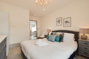 A bedroom with a large bed, bedside tables, a wardrobe, and a chandelier.