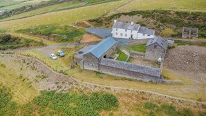 A rural property with a stone house, a fenced sheep field, and a view of the sea. - 3 Bed in Tywyn (oc-h32633) (Tywyn)