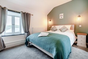 A bedroom with a bed, a nightstand, a window with curtains, and a wall-mounted light fixture. - 3 Bed in Tywyn (oc-h32633) (Tywyn)