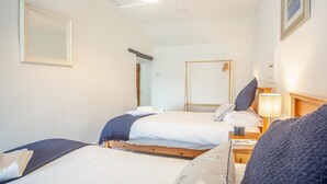 Habitación de hotel con dos camas, una mesita de noche con lámpara, un espejo y un cuadro en la pared.
