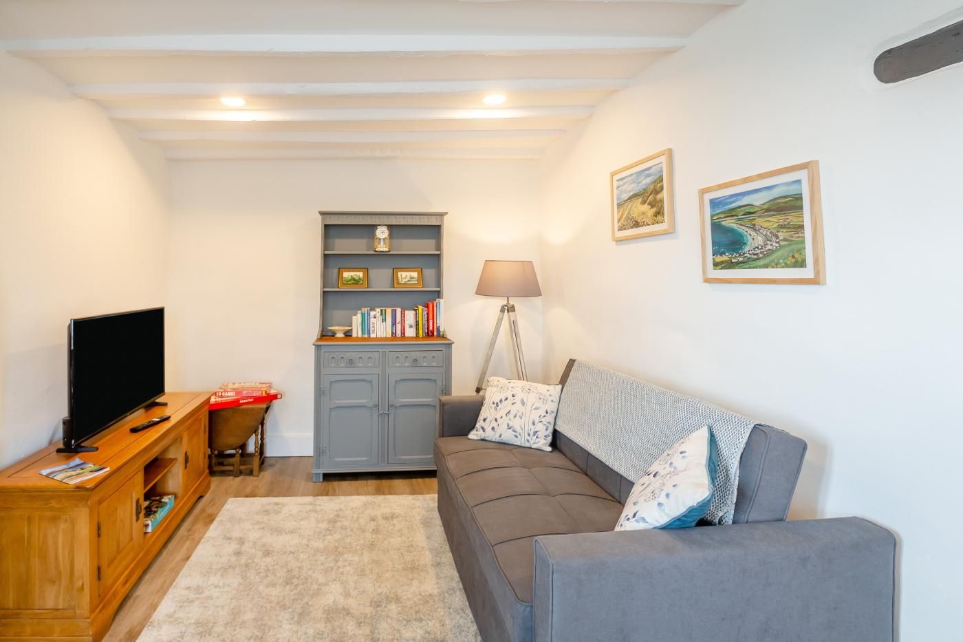 A living room with a television, a bookshelf, a sofa, and a lamp.