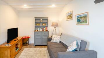 A living room with a television, a bookshelf, a sofa, and a lamp.