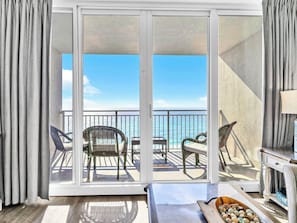 A balcony with a view of the ocean, furnished with wicker chairs and a table. - 🏝️Beach FRONT | 2 POOLS | Hot Tub | Emerald Beach 931🏝️ (Panama City Beach)