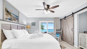A bedroom with a bed, a ceiling fan, a view of the ocean, a chair, and a wardrobe. - 🌊Beachfront | Dog Friendly | Incredible Gulf Views | Surfs Up🌊 (Panama City)