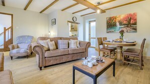 A spacious living room with a brown sofa, a dining table set with plates and cups, and a painting on the wall. - 2 Bed in Cray (oc-bow287) (Crai)