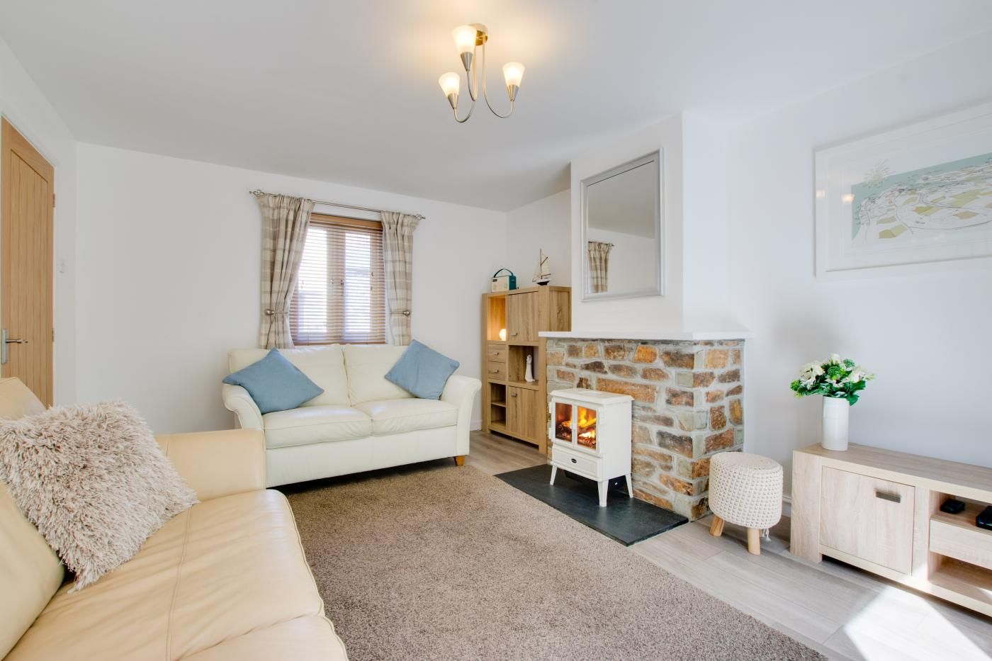A cozy living room with a white sofa, a stone fireplace, and a wooden cabinet.
