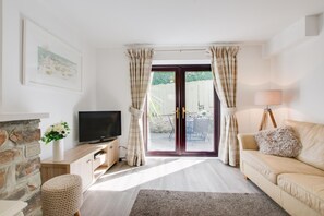 A living room with a television, a sofa, a lamp, a fireplace, and a view through a glass door.