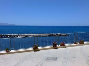A coastal view with a clear sky, a dock with boats, and potted plants on a balcony. - Apartment 'Perla Marina Primo Piano' with Balcony, Wi-Fi and Air Conditioning (Trappeto)