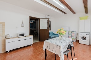 A compact kitchen with a microwave, toaster, and a table with a sunflower vase.