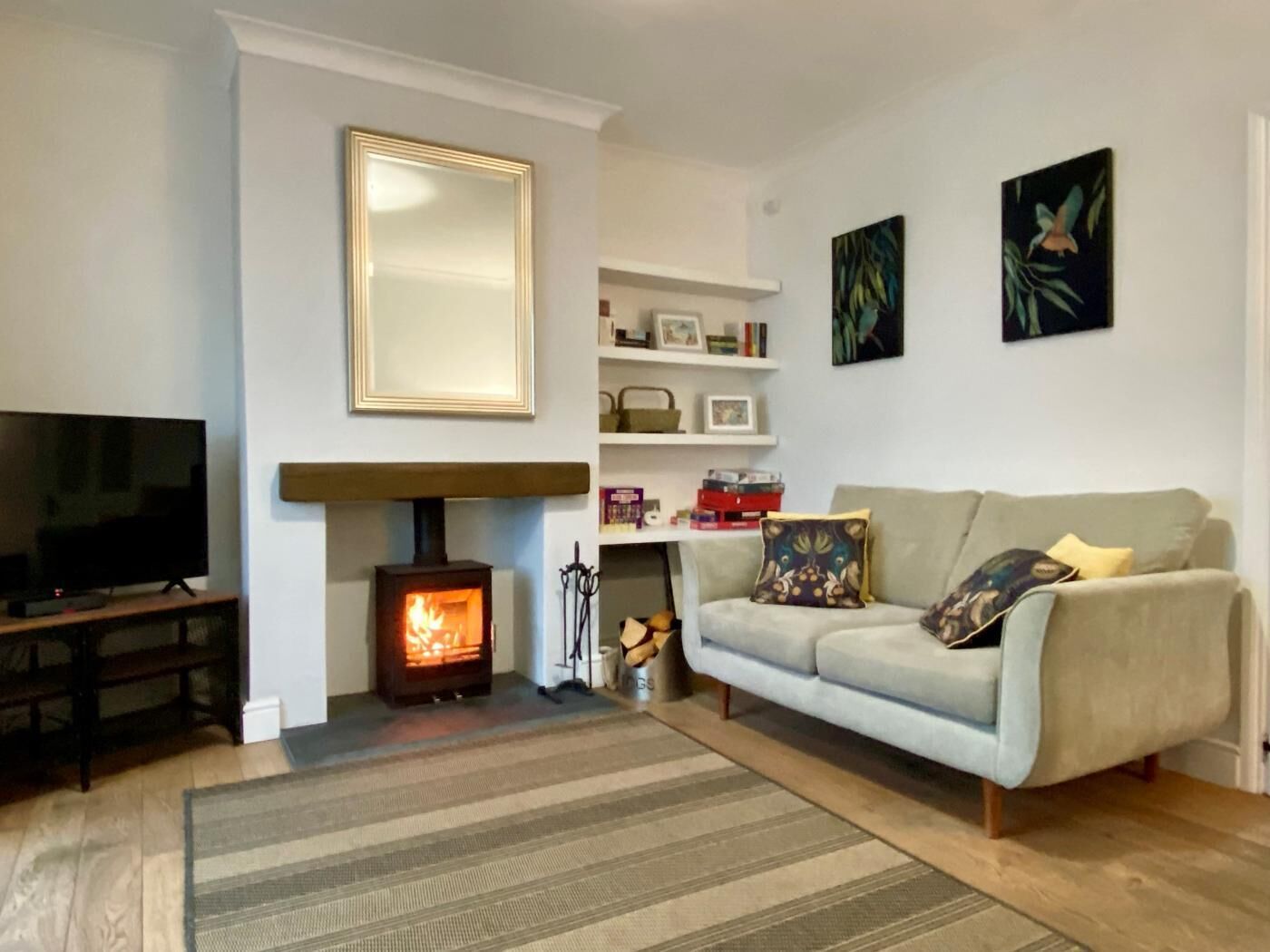 A living room with a fireplace, a sofa, a television, and a bookshelf.