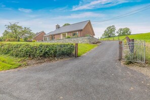A rural road leading to a house with a stone wall and metal gate. - 2 Bed in Penybontfawr (oc-b32943) (Penybontfawr)