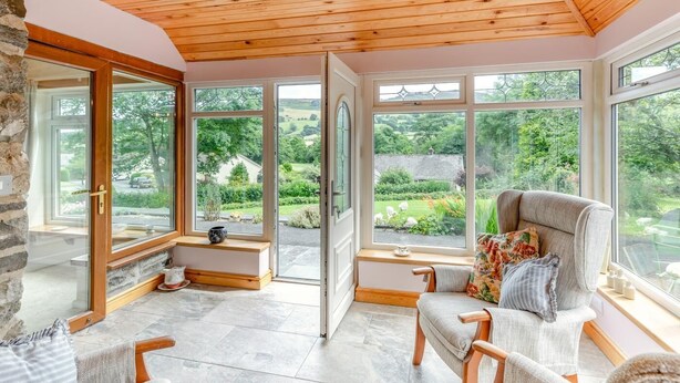 A sunlit room with large windows, a wooden ceiling, and a stone wall. - 2 Bed in Penybontfawr (oc-b32943) (Penybontfawr)
