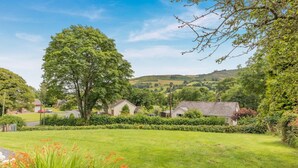 A rural landscape with houses, a large tree, and a grassy field. - 2 Bed in Penybontfawr (oc-b32943) (Penybontfawr)
