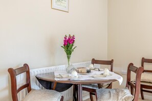 A dining table set for four with a vase of flowers, plates, and cutlery. - 2 Bed in Penybontfawr (oc-b32943) (Penybontfawr)