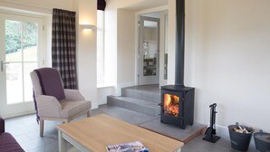 A cozy living room with a fireplace, a comfortable armchair, and a wooden table. - 3 Bed in Low Row (oc-ds1030) (Low Row)