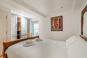 Une chambre d’hôtel avec un grand lit, une armoire, une chaise et une fenêtre.