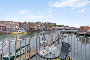 Une vue sur le port avec des bateaux amarrés, une table avec de la nourriture et des boissons, et une chaise.