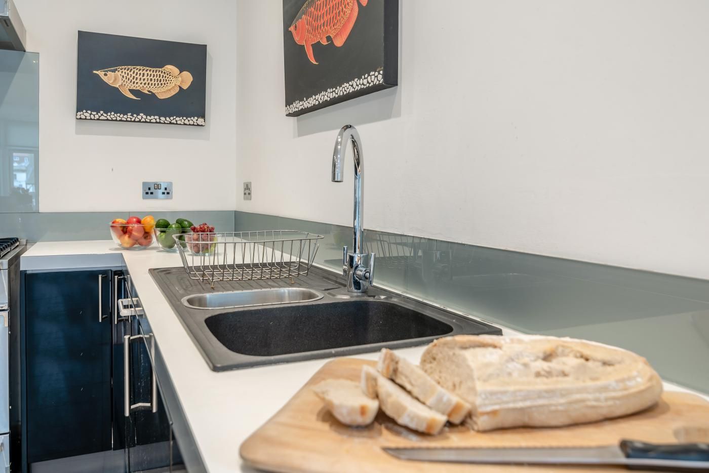 Eine moderne Küche mit einer doppelten Spüle, einer Obstschale und einem Brot auf der Arbeitsfläche.