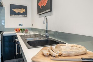 Eine moderne Küche mit einer doppelten Spüle, einer Obstschale und einem Brot auf der Arbeitsfläche.