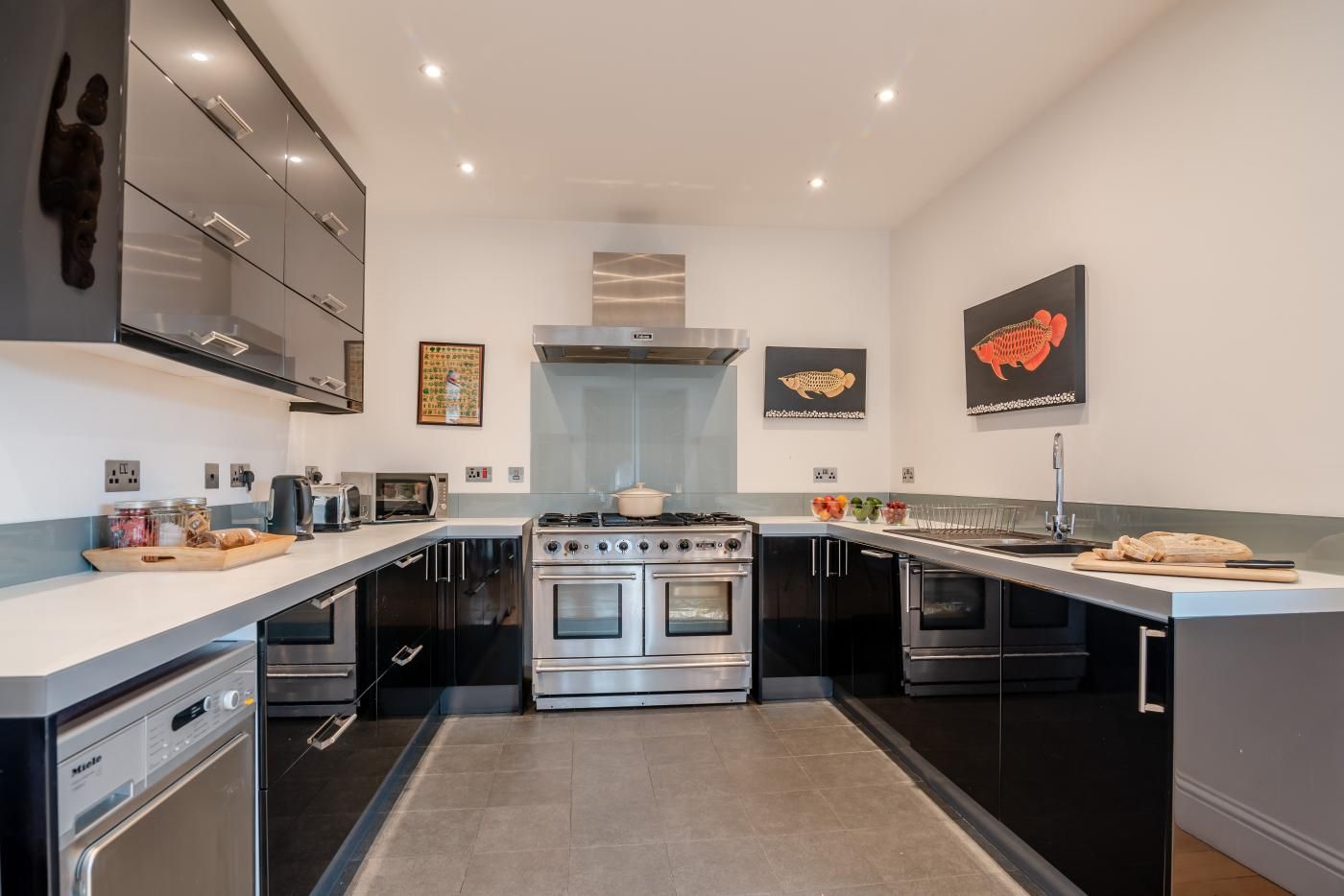Une cuisine moderne avec un îlot central servant de table de cuisson, des meubles noirs et un plan de travail blanc.