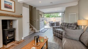 Ein gemütliches Wohnzimmer mit Kamin, einer Couch, einem Couchtisch und einem Essbereich mit Sitzgelegenheiten im Freien.
