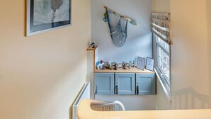 A room with a crib, a shelf with books and a framed certificate, a wall-mounted hammock, and a framed picture. - 1 Bed in Whitby (oc-w121) (Whitby)