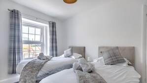 Ein Hotelzimmer mit zwei Betten, einem Fenster mit Vorhängen, Balkonblick und einer modernen Lampe.