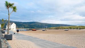 Ein Strand mit befestigtem Weg, einem weißen Gebäude und mehreren Booten.