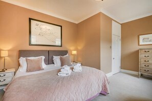Ein Schlafzimmer mit einem Bett, Nachttischen, einer Kommode und Bildern an den Wänden.