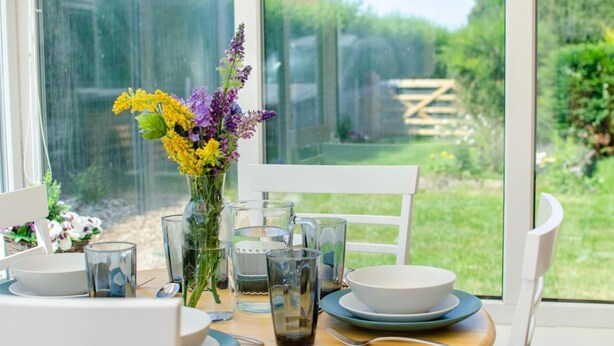 A dining table set with plates, bowls, glasses, and cutlery, with a vase of flowers in the center. - 2 Bed in Docking (oc-2212) (Docking)