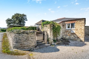 A stone house with a gravel driveway, a wooden gate, and a small porch. - 1 Bed in Padstow (oc-p00554) (Saint Merryn)