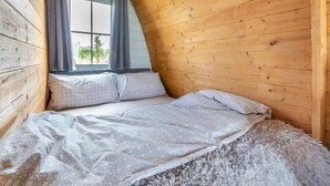 Um quarto aconchegante com telhado inclinado, uma cama, almofadas e um tapete fofo.