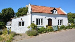 Valkoinen rakennus, jossa on punatiilestä tehty katto, kyltti, jossa lukee »HAPPISBURGH», ja vihreä portti.