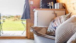 Um quarto aconchegante com sofá, pequena cozinha e vista para o exterior.