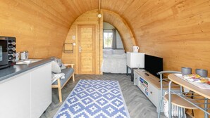 Um interior acolhedor em madeira, com cozinha, sala de jantar e área de dormir.