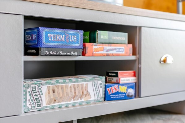 A shelf with board games and a Monopoly set.