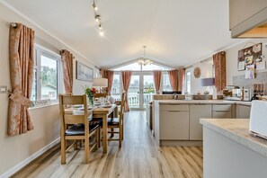Eine moderne Küche mit Holzboden, einem Essbereich mit Tisch für vier Personen und Blick ins Freie.
