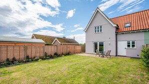 A residential property with a well-maintained lawn, a patio with outdoor furniture, and a house with a tiled roof and a grey facade. - 3 Bed in Wangford (oc-75sare) (Wangford)