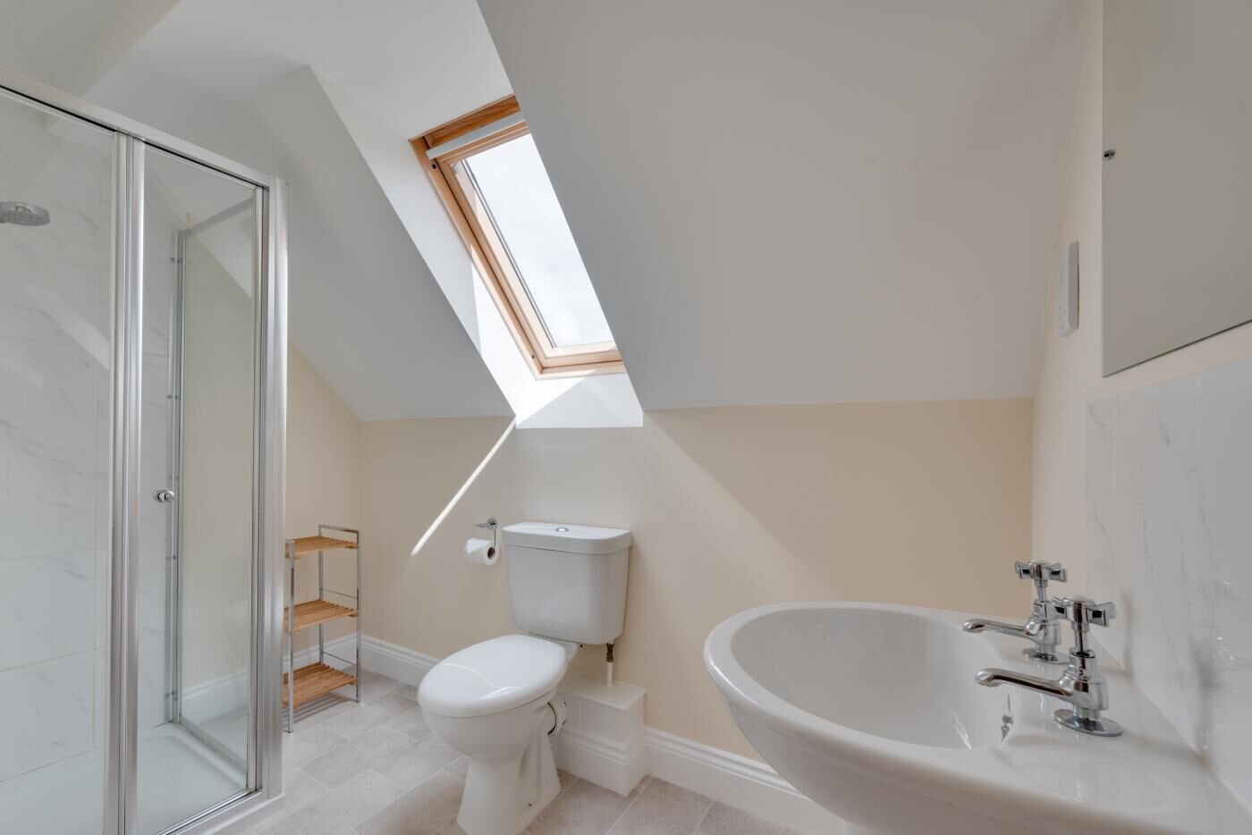 A modern bathroom with a skylight, a glass shower enclosure, a toilet, and a freestanding bathtub.