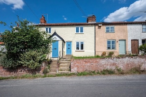 A row of terraced houses with a brick wall and a tree in front.