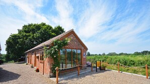 A brick building with a sloped roof, large windows, and a gravel driveway. - 1 Bed in Acle (oc-1256) (Limpenhoe)