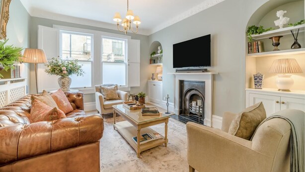 A living room with a leather sofa, a coffee table, a fireplace, and a television mounted on the wall. - 2 Bed in Bath (oc-bhr25) (Bath)
