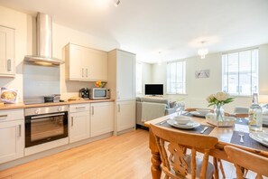 A modern kitchen with a built-in oven, microwave, and a stainless steel range hood. - 2 Bed in Seahouses (oc-nb1944) (Seahouses)