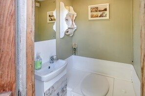 A bathroom with a white sink, a toilet, and a bathtub. There are two framed pictures on the wall. - 1 Bed in Trefeitha (oc-h32936) (Trefeitha)
