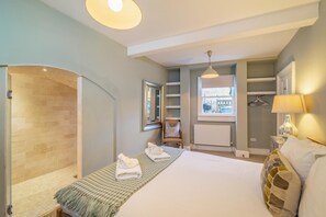 A modern hotel room with a large bed, a walk-in shower, a small seating area, and a window with a view. - 3 Bed in Bath (oc-bhr26) (Bath)
