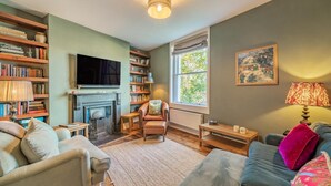 A cozy living room with a fireplace, bookshelves, a television, and comfortable seating. - 3 Bed in Bath (oc-bhr26) (Bath)